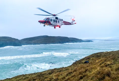 The R151 HM Coastguard Rescue Helicopter lifts a stranded surfer from rocks at Farr Bay, Scotland. 