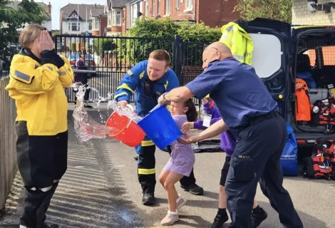 Miss Mills wears HM Coastguard kit as a bucket of water is thrown at her by two coastguards and a pupil