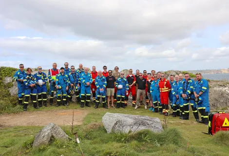 A group photo by the cliff of Coastguard Rescue Officers and Cornwall Air Ambulance personnel