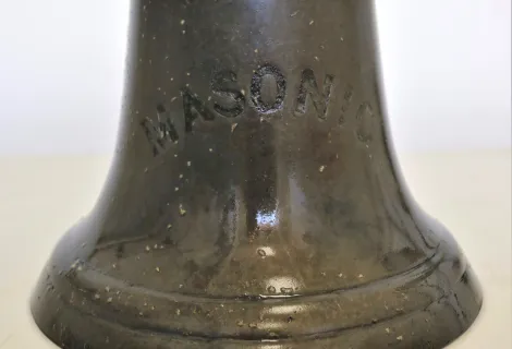 A close up picture of the bell bearing the ship name, Masonic