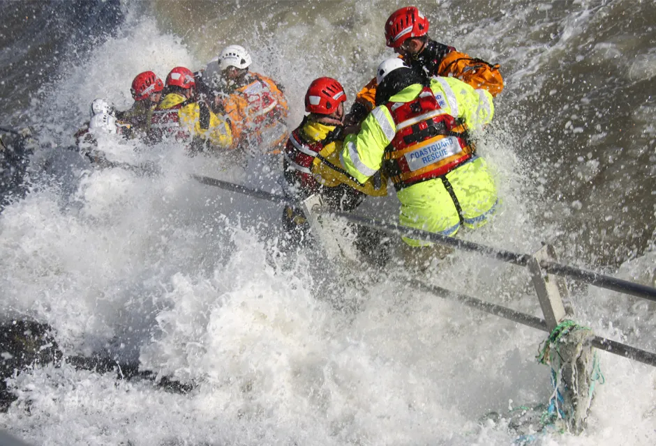 Coastguard rescue officers engulfed in sea spray as they practice practice a water rescue