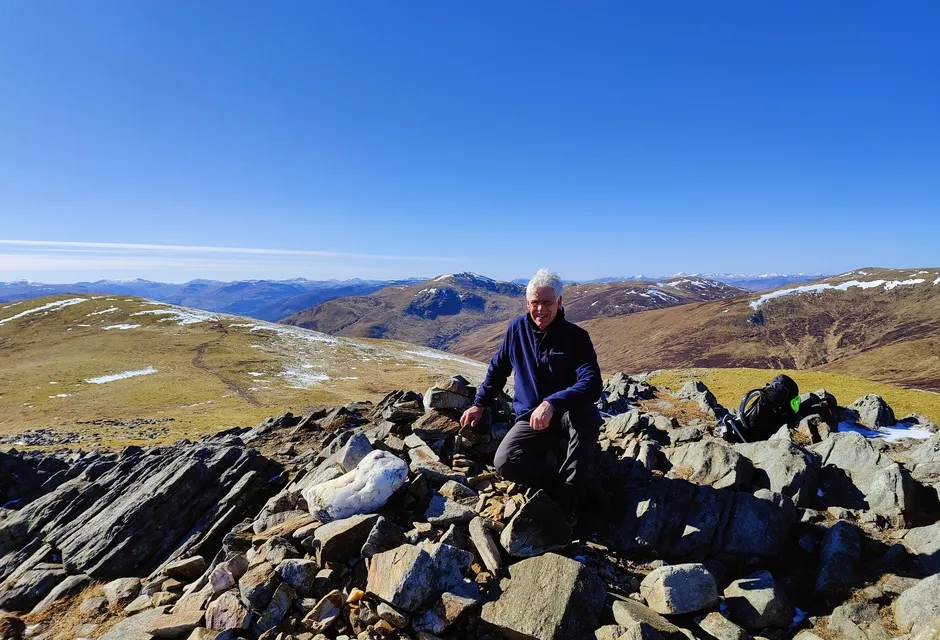 Man sits at the summit of Creag Mhor with a stunning view 