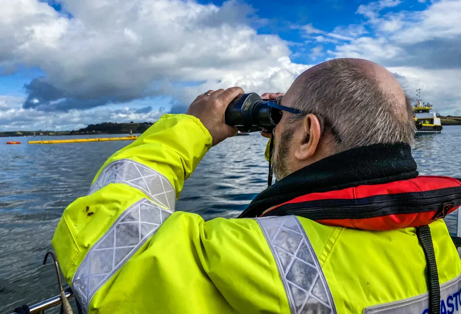 A Counter Pollution and Salvage officer watches out to sea through binoculars