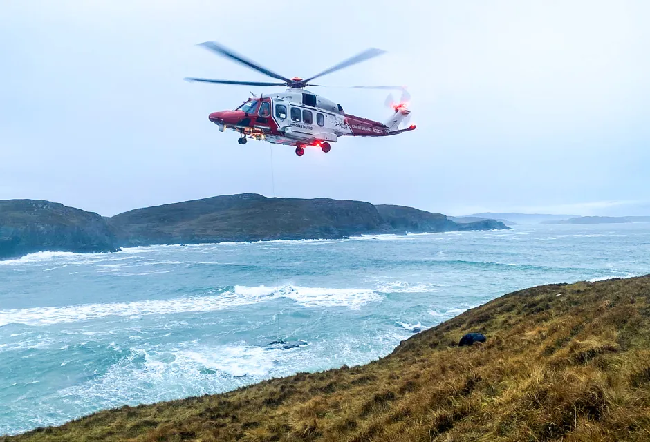 The R151 HM Coastguard Rescue Helicopter lifts a stranded surfer from rocks at Farr Bay, Scotland. 