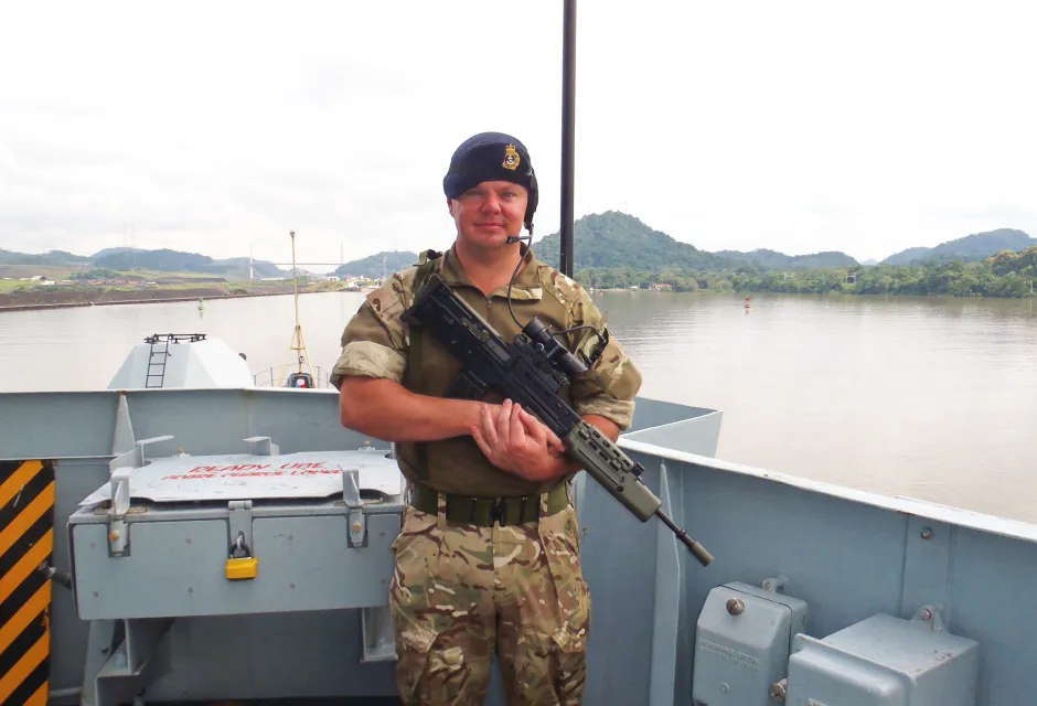 Jon Oliver on the deck of a vessel wearing Royal Navy uniform