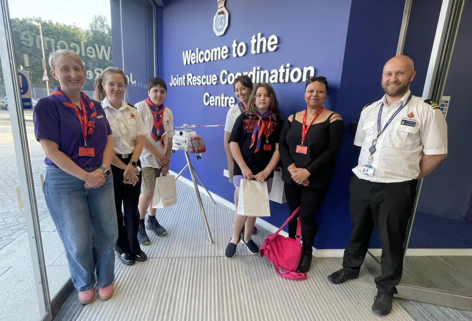 Scouts, parents and coastguards stand in front of the Joint Rescue Coordination Centre entrance sign