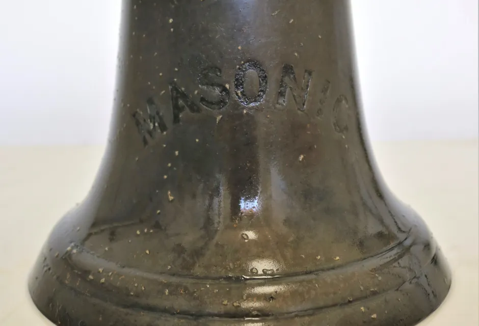 A close up picture of the bell bearing the ship name, Masonic
