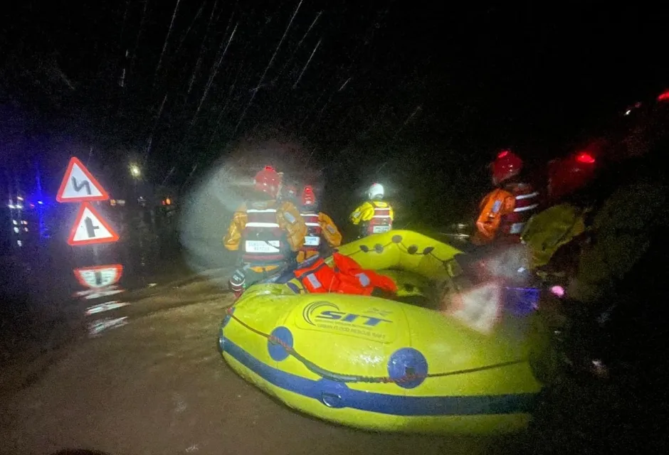 Coastguards steer a life raft through flood water