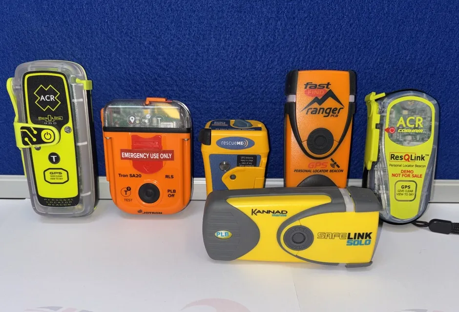 Six different makes of PLB, with colours of bright orange and yellow, are lined up against a blue background